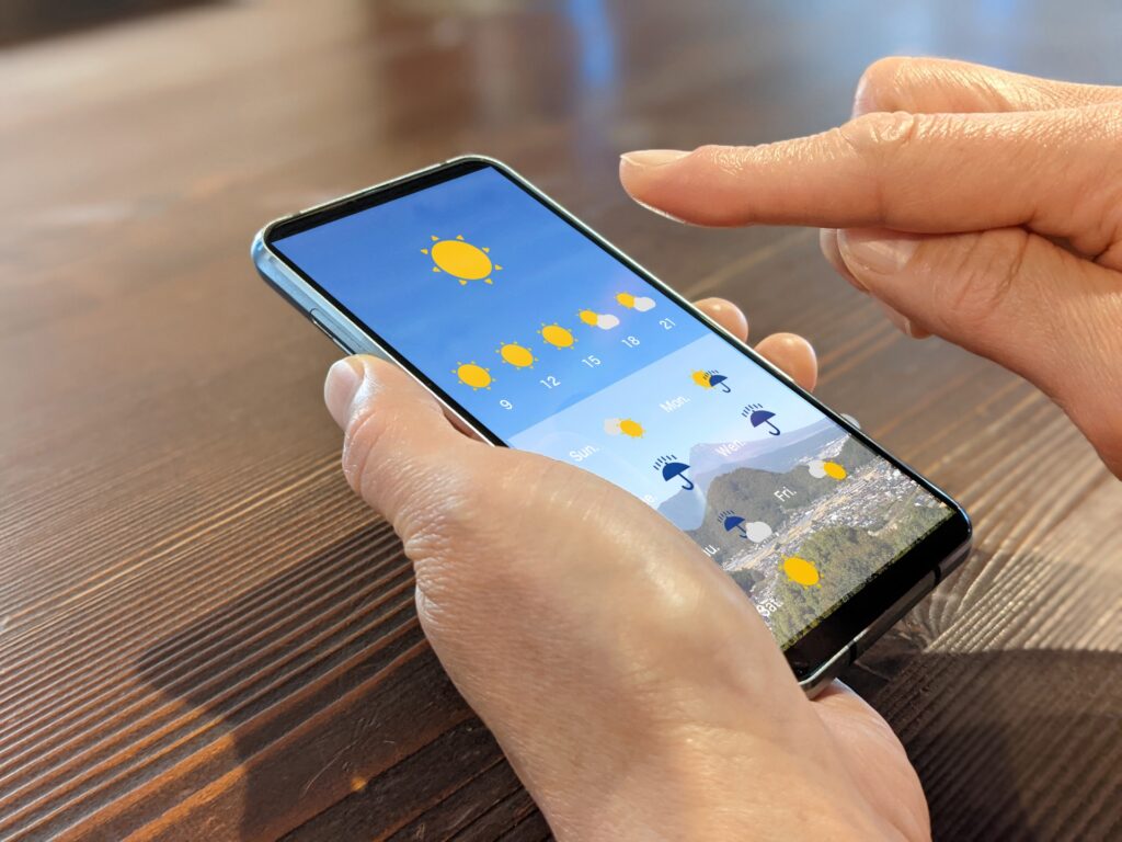 スマホ 上から天気予報をチェックしている人