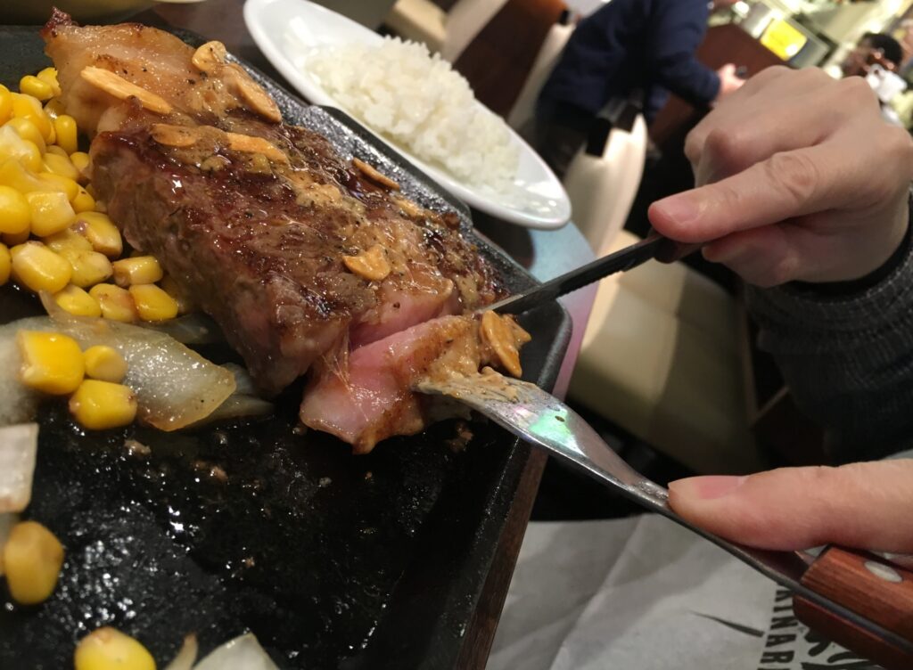 ステーキ店でステーキを食べている人