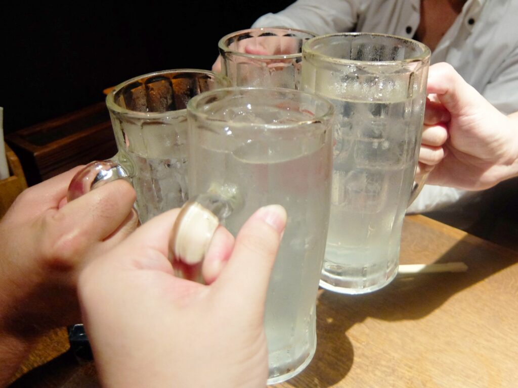 友達とチューハイを飲んでいる人