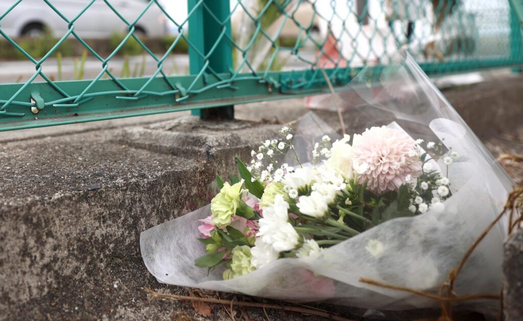 事故現場で花束を供えている人